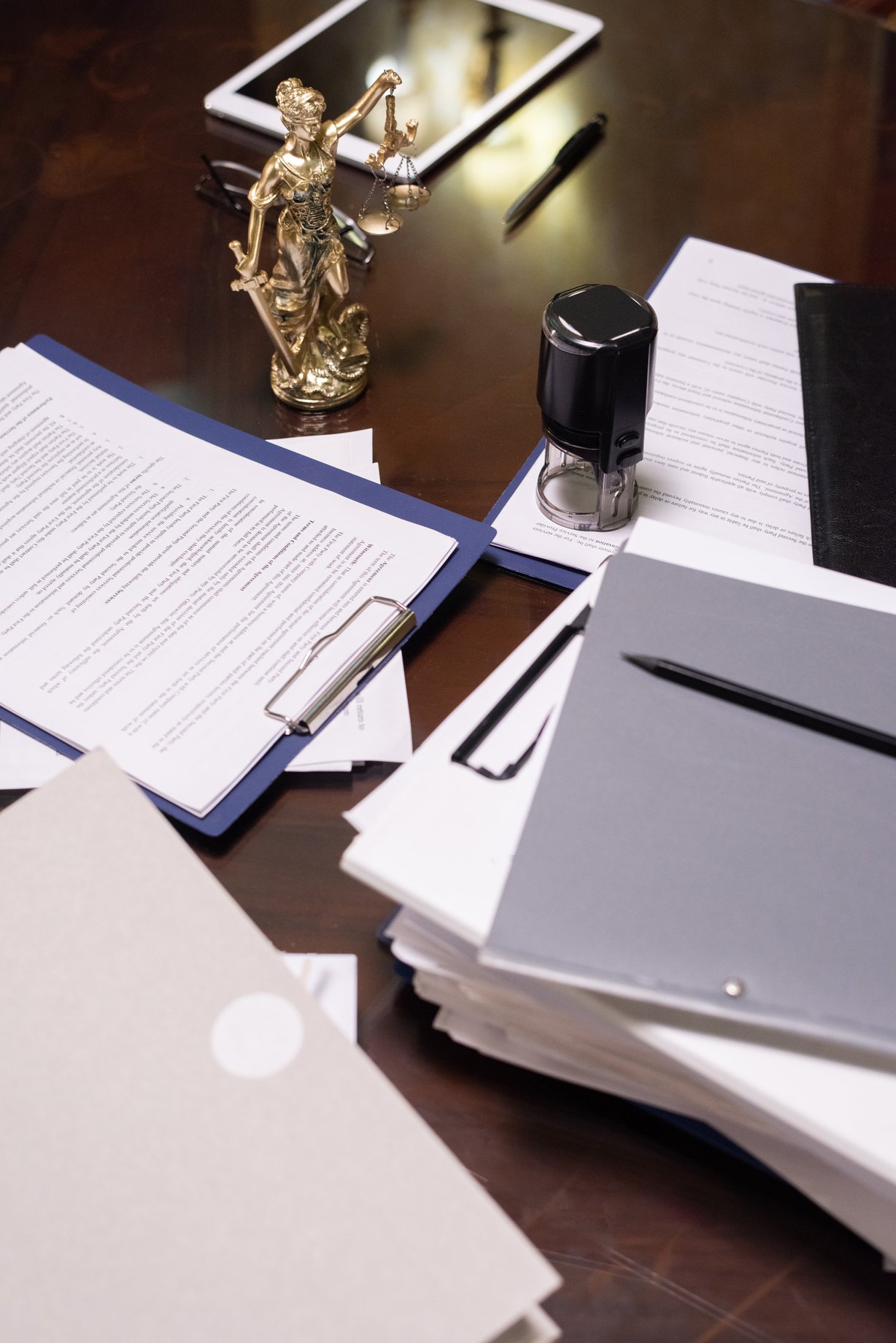 Group of objects and several stacks of juridical papers in clipboards and folders on workplace of lawyer